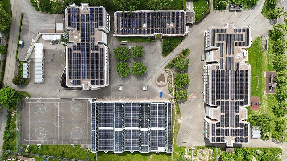 Drohnenaufnahem des Schulshauses Margelacker mit 4 Gebäuden, darauf Solaranlagen